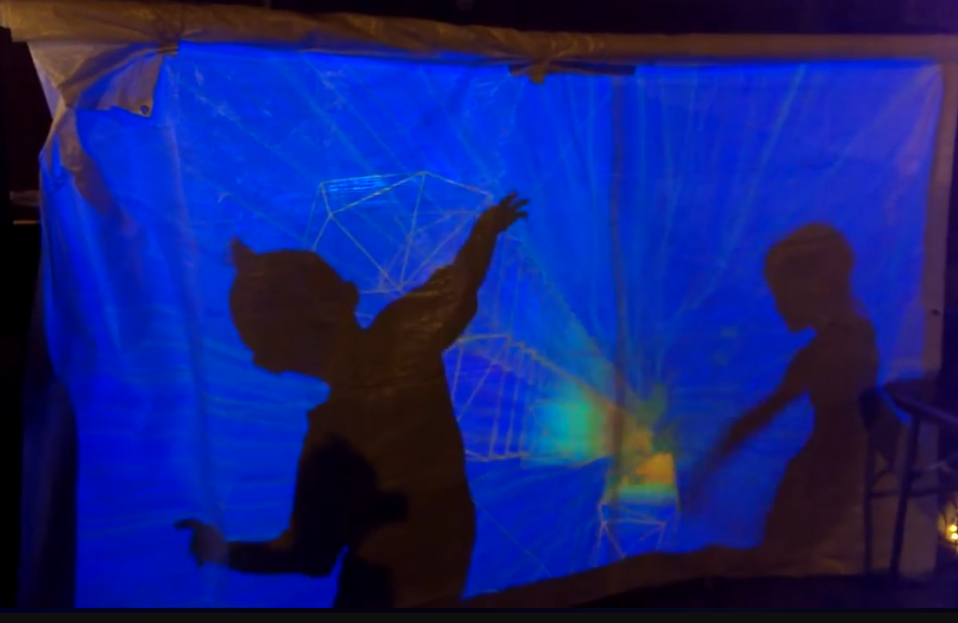 Audience silhouettes moving in front of blue sound-reactive Xibaba projections